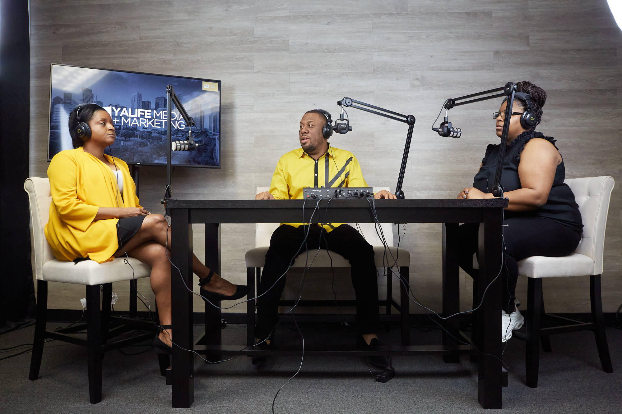 Three hosts recording a podcast episode at YaLife Studios in Houston